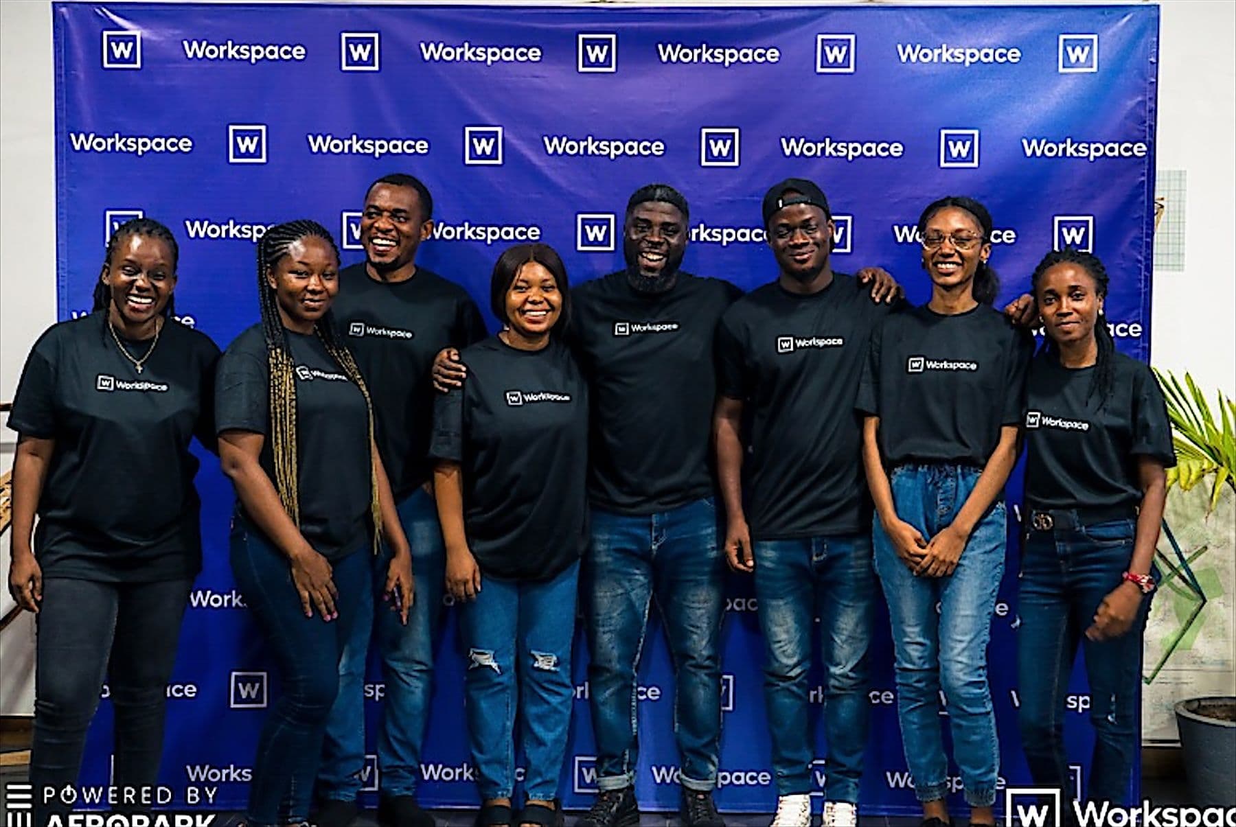 The Workspace team in branded T-shirts in front of a Workspace backdrop